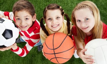 Image of happy friends on the grass with balls looking at camera